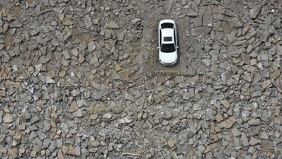 Workers demolish car park around one car