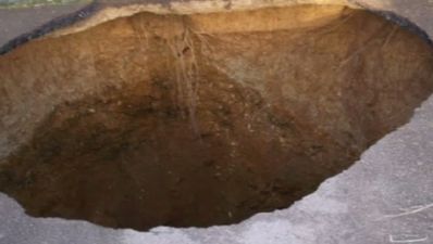 Pic: 30-foot deep sinkhole appears in driveway and swallows car