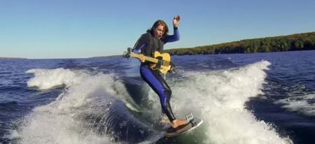 Video: A guy playing electric guitar while wake boarding out the back of a speedboat