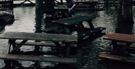 PIC: Two boys stay on the pints in a beer garden even though it’s completely flooded