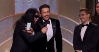 Tommy Wiseau tries to grab the microphone after James Franco’s win at the Golden Globes